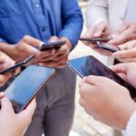 Várias mãos segurando celulares diferentes