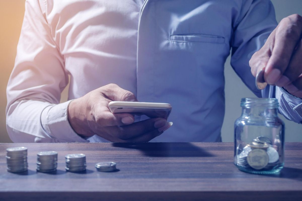 Homem com celular organizando a vida financeira Homem com celular organizando a vida financeira
